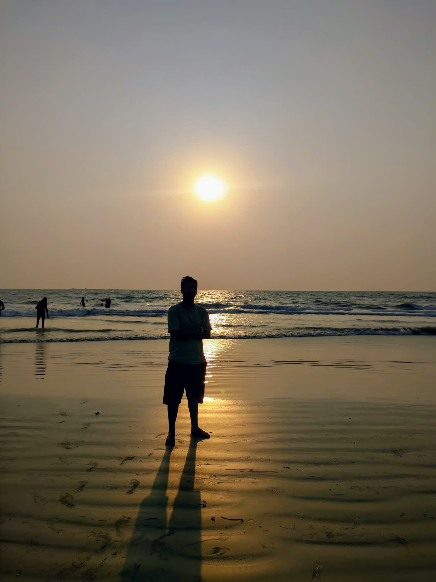 Aryan’s silhouette on wet sand facing the sun setting over the sea